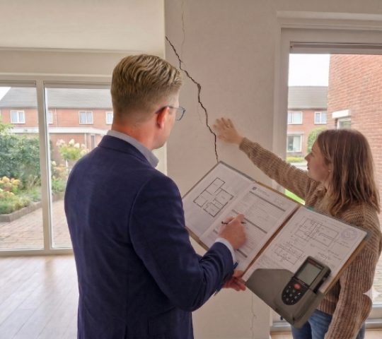 Schade expert beoordeelt een bouwkundig gebrek aan een aanbouw.